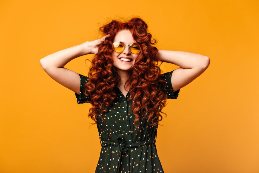 blithesome-european-girl-touching-ginger-hair-laughing-studio-shot-cheerful-young-woman-sunglasses-posing-yellow-background-1024x683